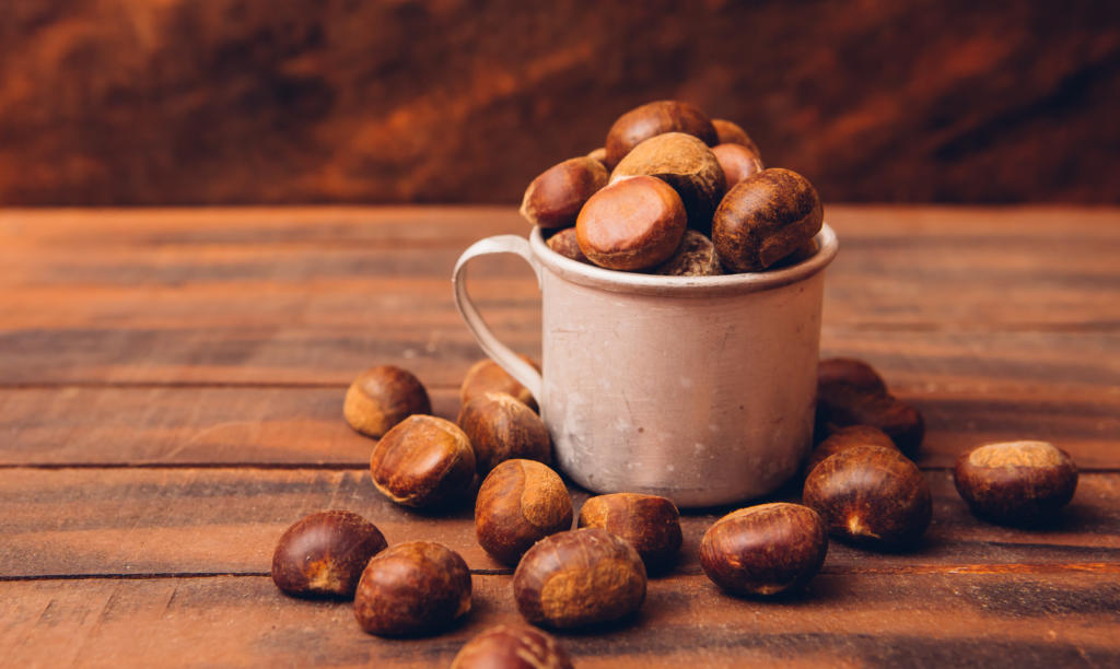 chestnuts in cup and around on dark wooden table