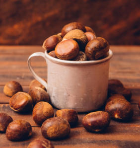chestnuts in cup and around on dark wooden table