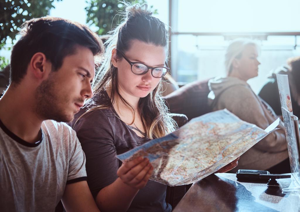 portrait young couple sitting outdoor caf planning itinerary their journey